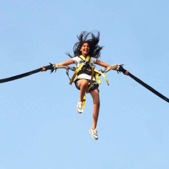Femme dans le ciel  sautant en Bungee Ejection, attachée à deux élastiques