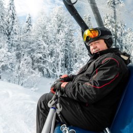 Un homme de plus de 60 ans sur un télésiège dans un paysage enneigé