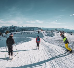 Groupe de jeunes skieurs et snowboarder qui skient avec un ciel bleu en fond