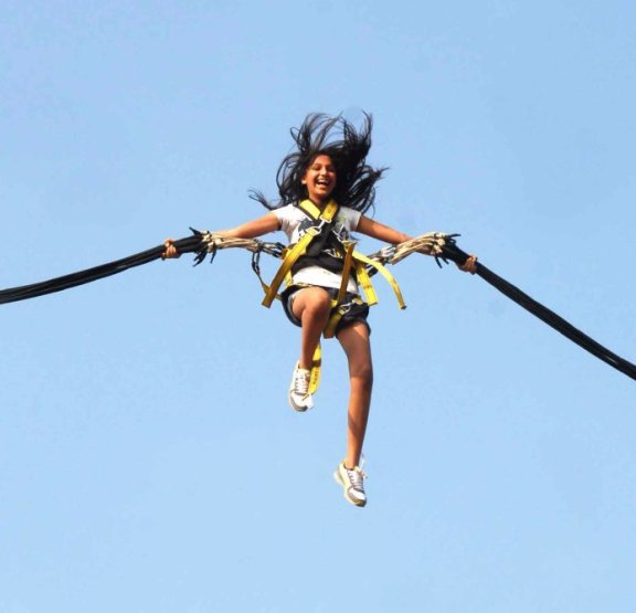 Femme dans le ciel sautant en Bungee Ejection, attachée à deux élastiques